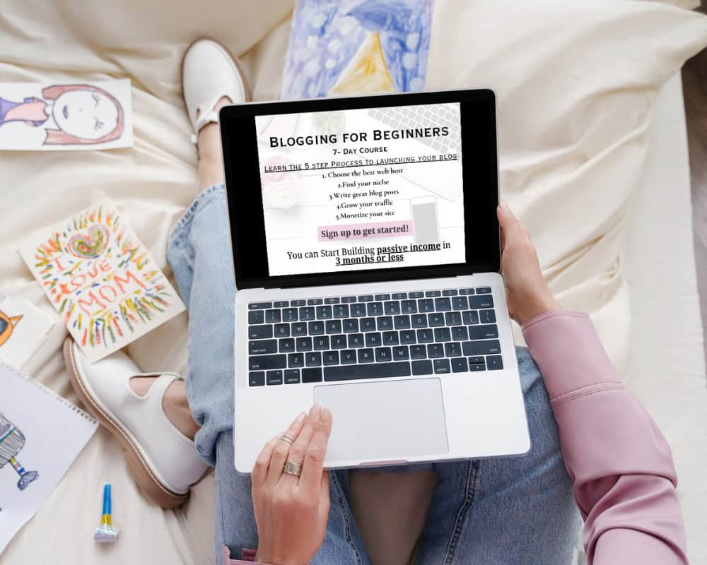 how to start a blog free course - woman sitting on bed with laptop and other stationary around her