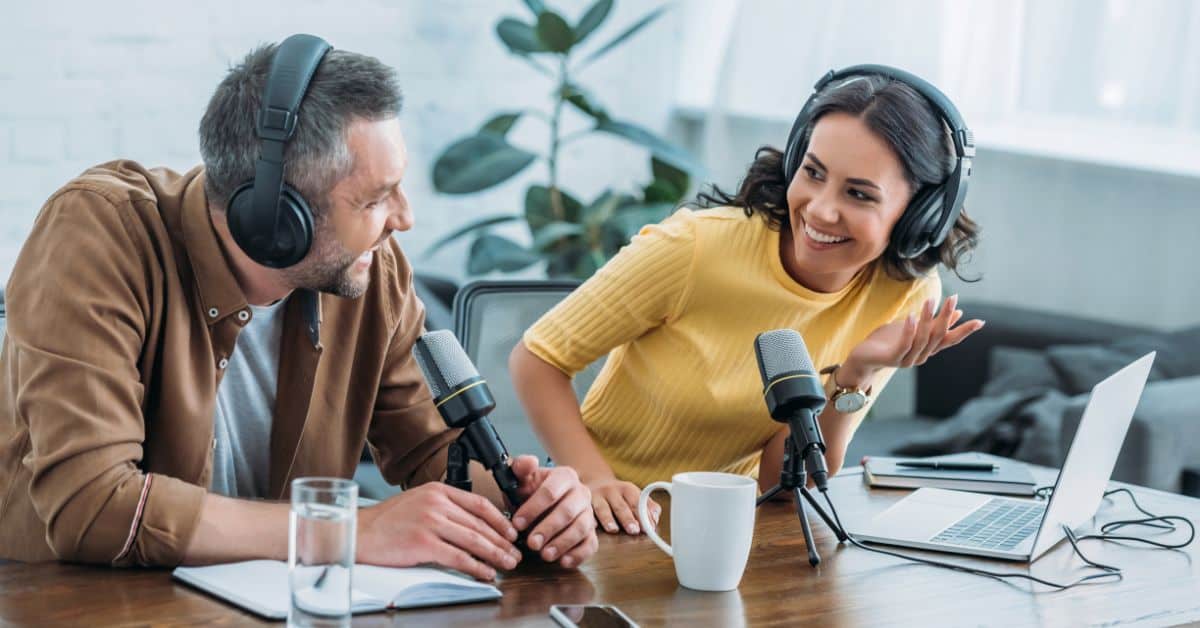 man and woman sitting at table with podcast mircophone - best podcasts for entrepreneurs