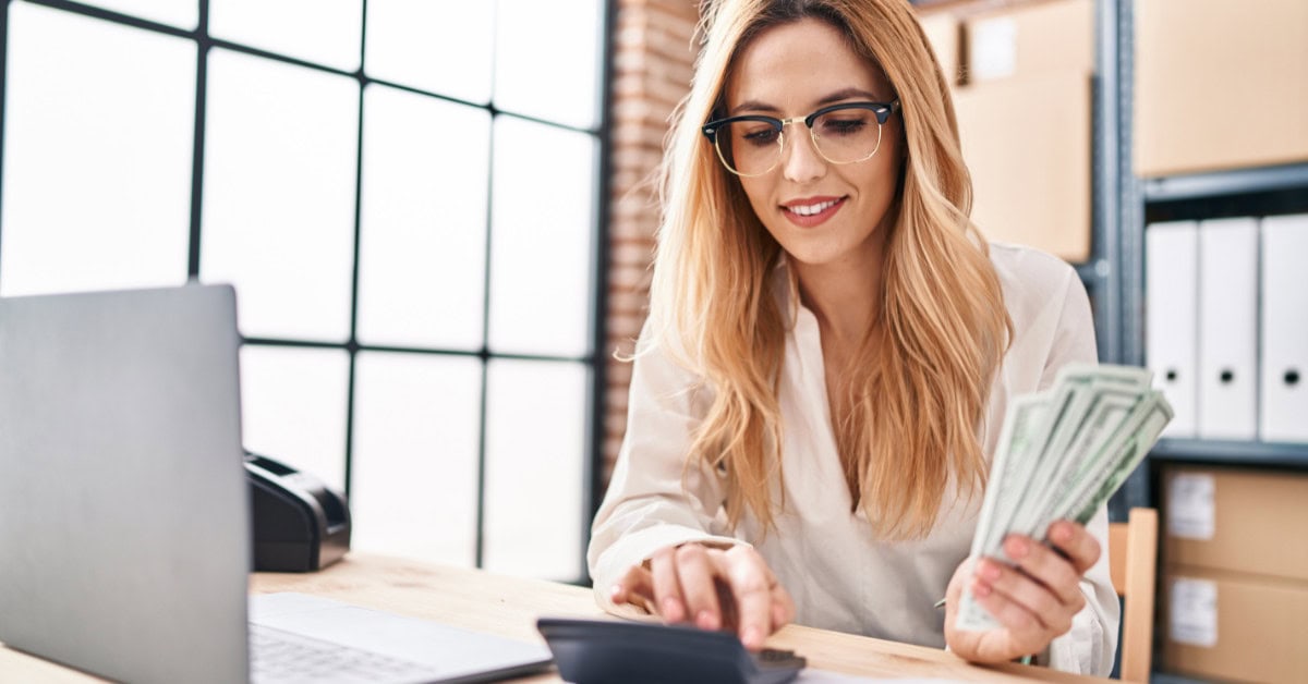 pretty woman smiling while holding cash at desk - how to make money blogging